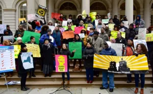 A group of community members and organizers rallying for public banking on the steps of a city building